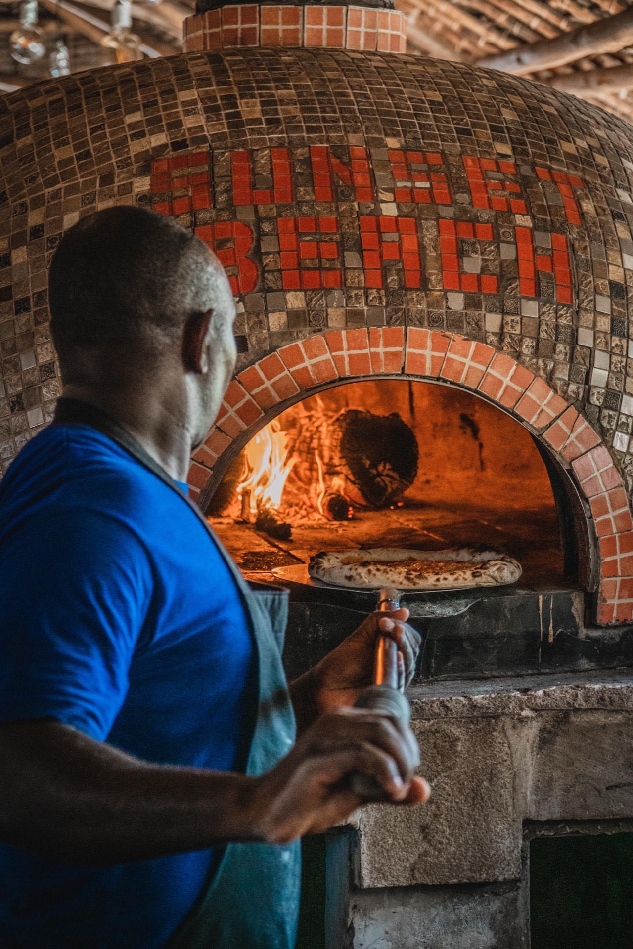 Pizzaiolo pulling a fresh pizza from the Sunset Beach wood-fired oven
